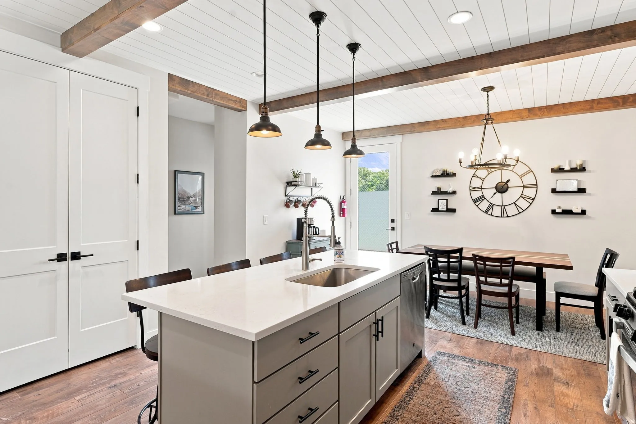 Spacious kitchen island with an undermount sink and matte black faucet, featuring a white countertop and grey cabinetry