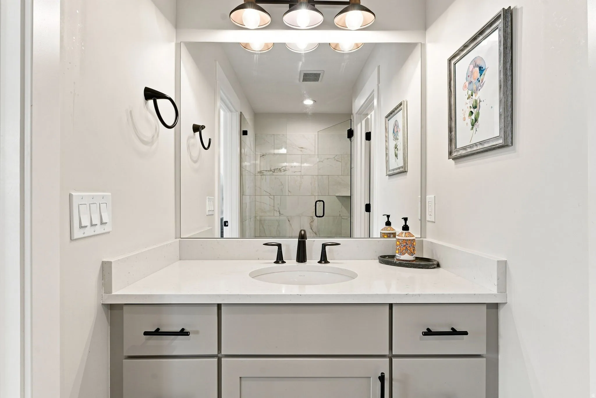 Vanity with integrated sink, stone countertop, matte black faucet, and modern cabinetry with black hardware