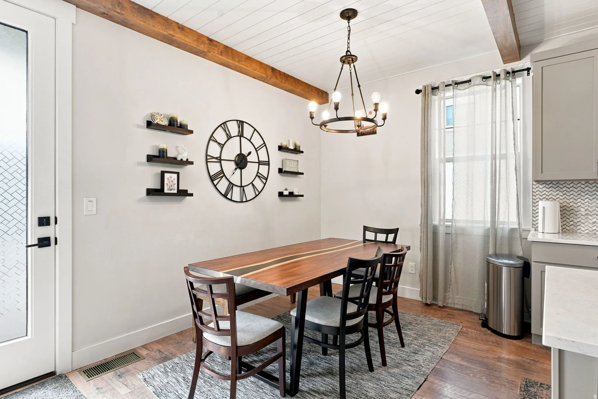 Hardwood flooring, exposed ceiling beams, a wood plank ceiling, an overhead chandelier, and a frosted glass door