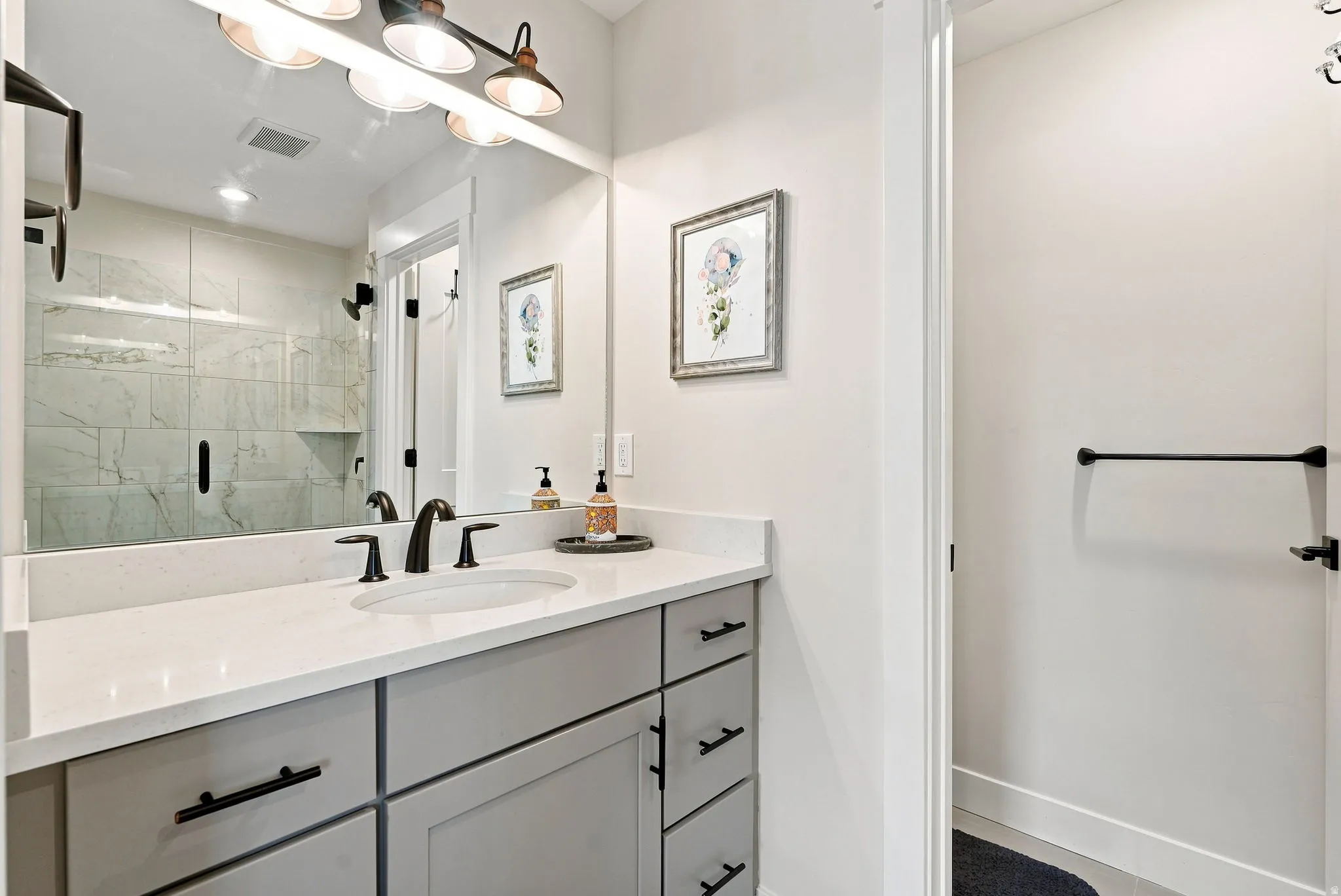 Vanity with light-toned countertop, undermount sink, and matte black fixtures