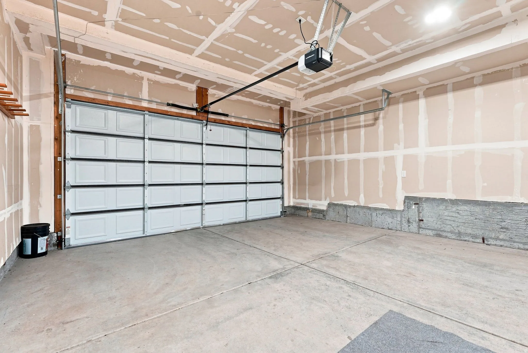 Spacious garage featuring a modern glass-panel overhead door, concrete flooring, coffered ceiling with recessed lighting, and a projector mount for enhanced functionality