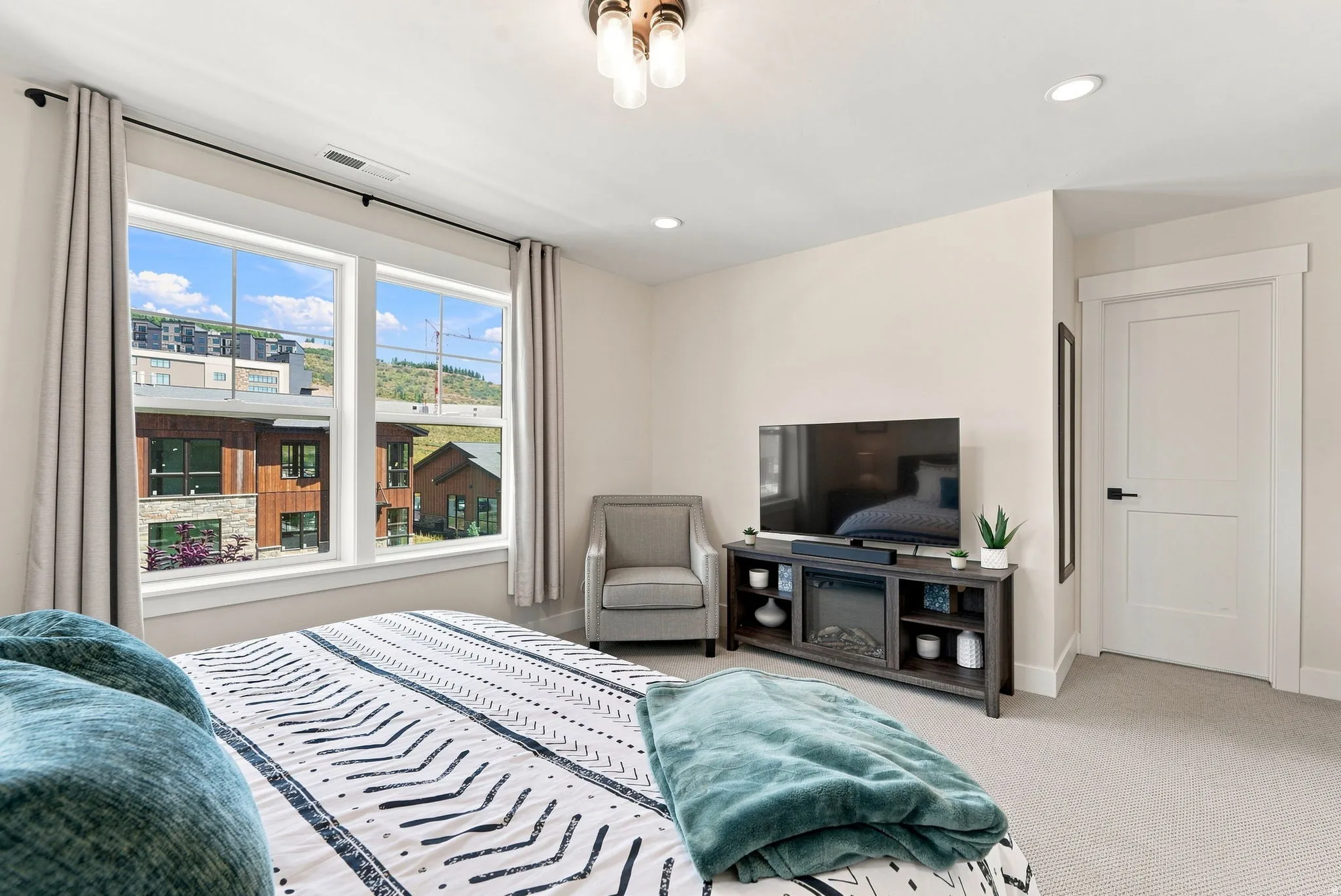 Dual pane windows, recessed lighting, ceiling-mounted light fixture, white interior door with dark hardware, and light-colored carpet