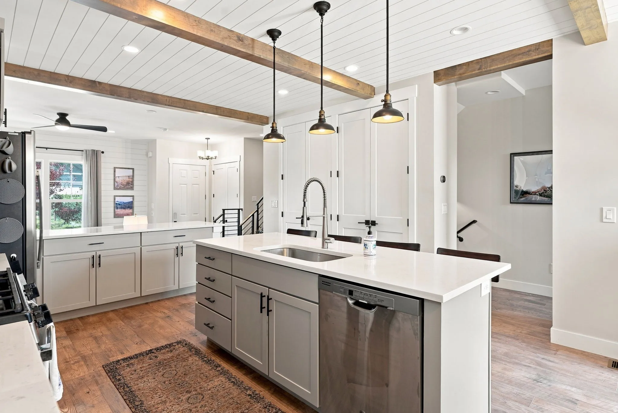 Kitchen featuring an island with a stainless steel sink, light grey cabinetry, and white countertops