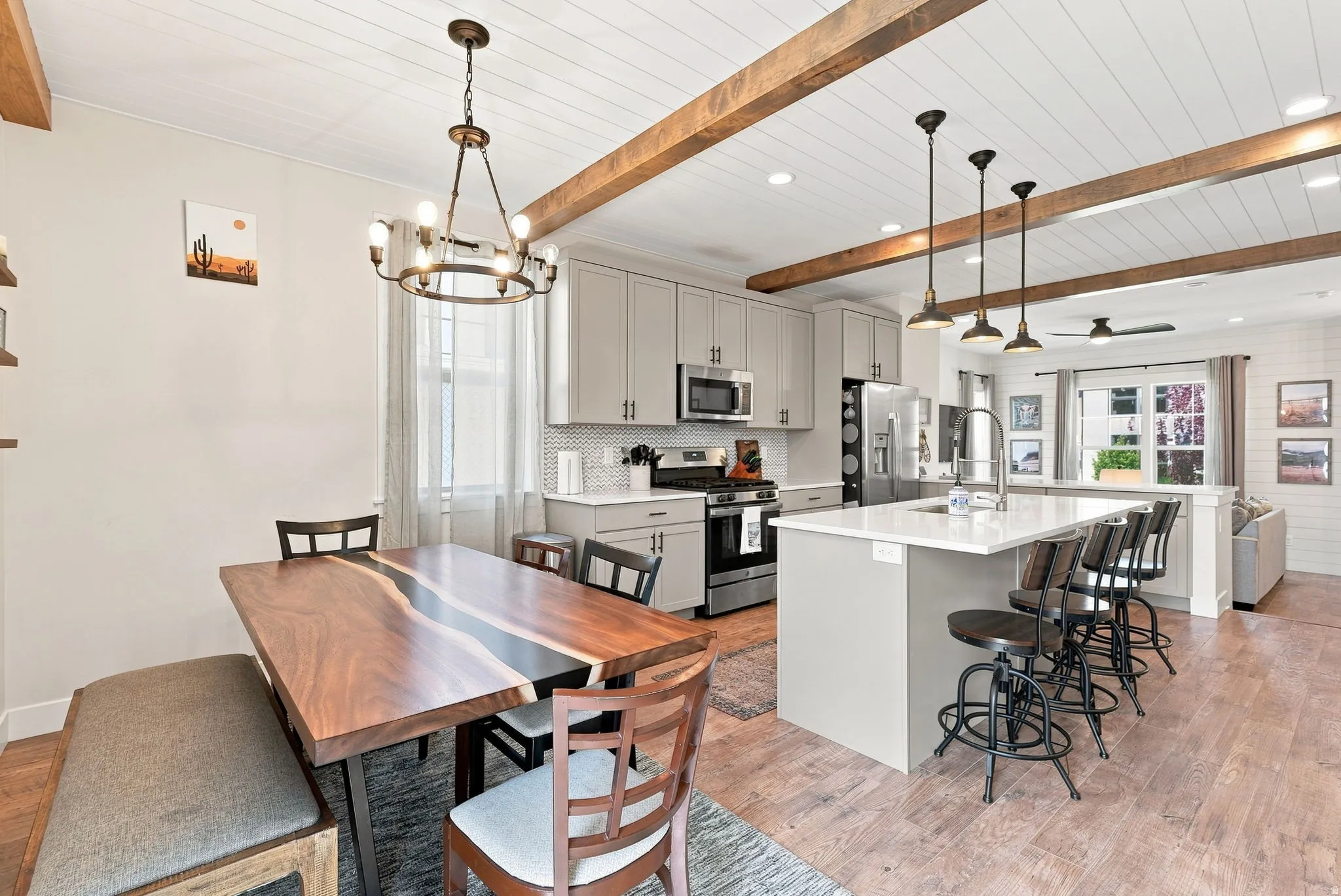Kitchen featuring light-toned cabinetry, stainless steel appliances, a center island with seating, a tile backsplash, and wood-finish flooring