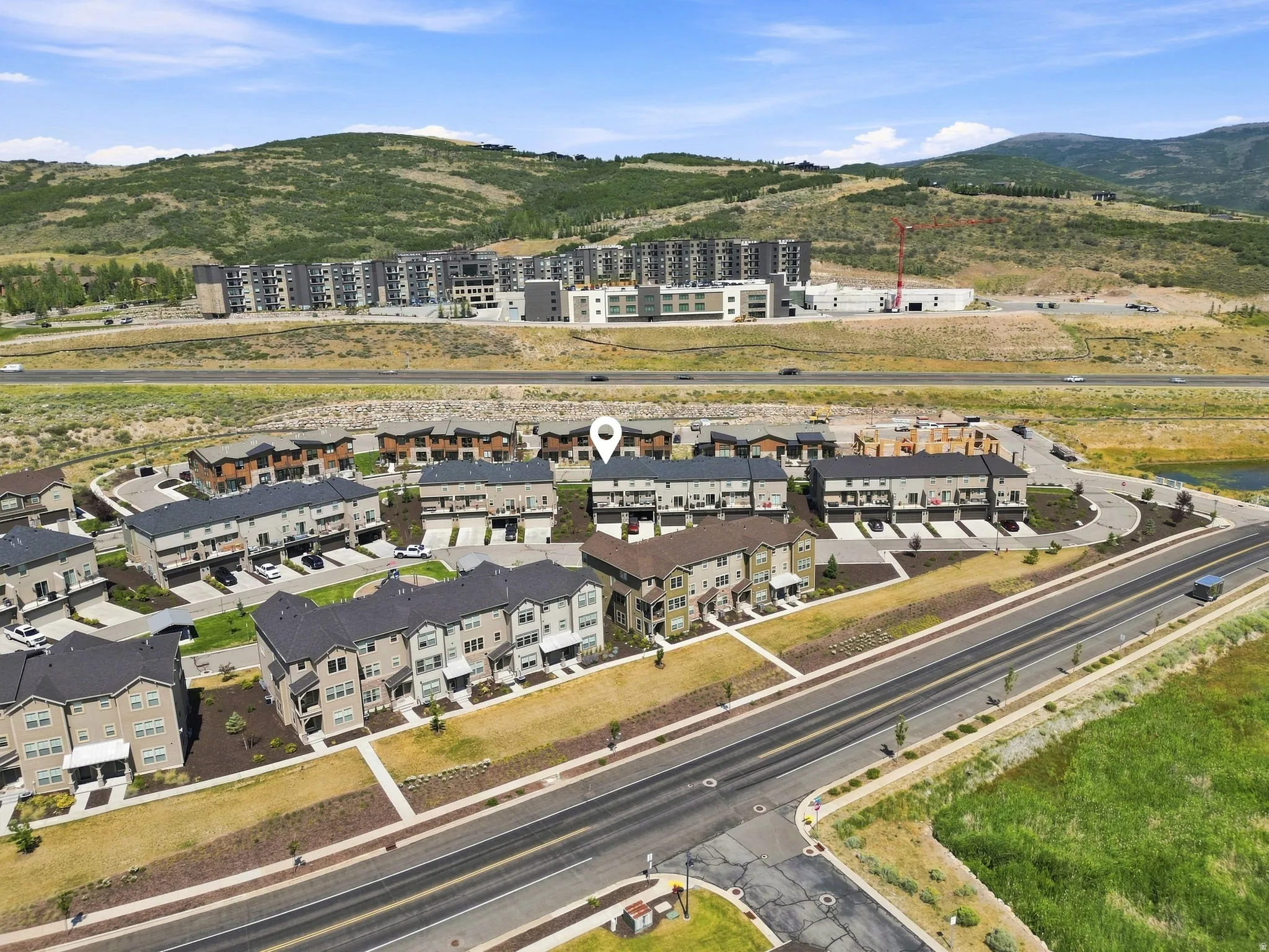 Aerial perspective showcasing a residential community with multi-story townhomes, structured roadways, and natural landscaping