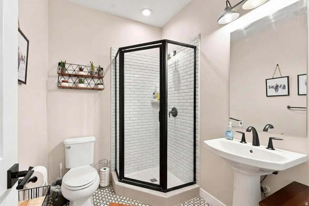 Walk-in shower with black-framed glass enclosure, subway tile surround, and matte black fixtures