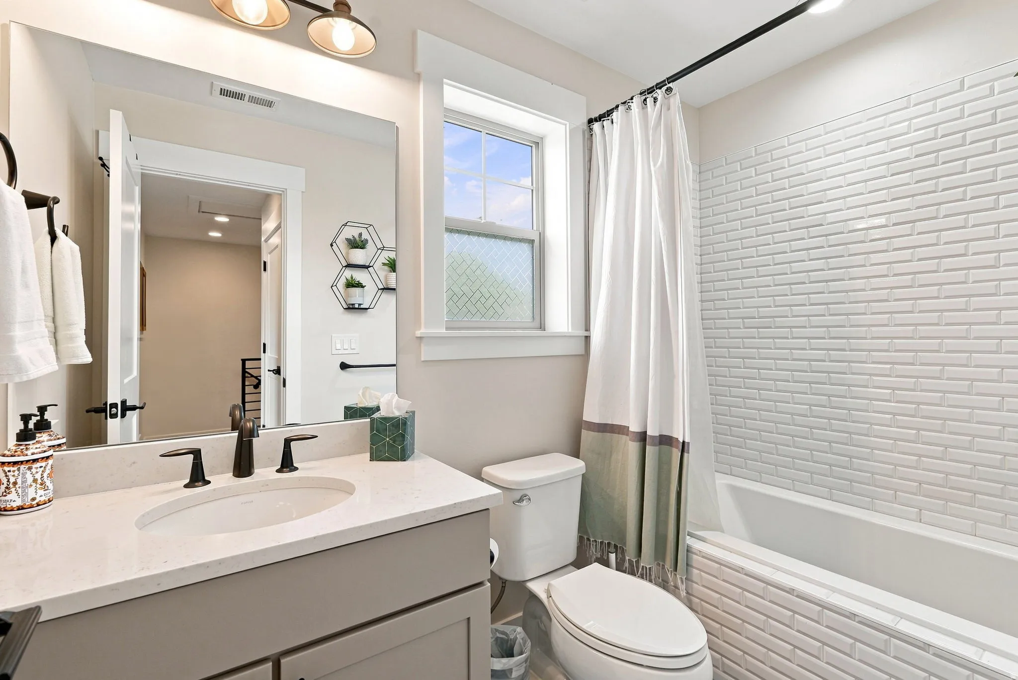 Vanity with integrated sink and dark bronze faucet, framed mirror, and two-light fixture