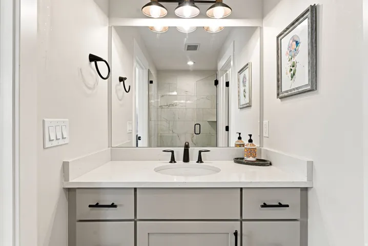 Vanity with integrated sink, stone countertop, matte black faucet, and modern cabinetry with black hardware