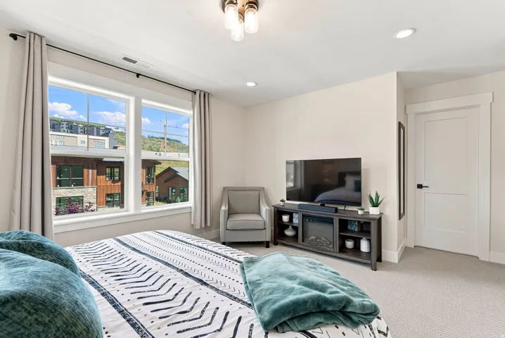 Dual pane windows, recessed lighting, ceiling-mounted light fixture, white interior door with dark hardware, and light-colored carpet