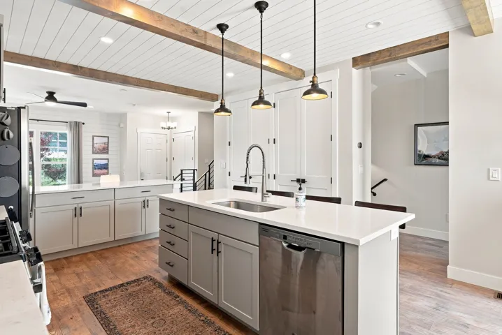 Kitchen featuring an island with a stainless steel sink, light grey cabinetry, and white countertops