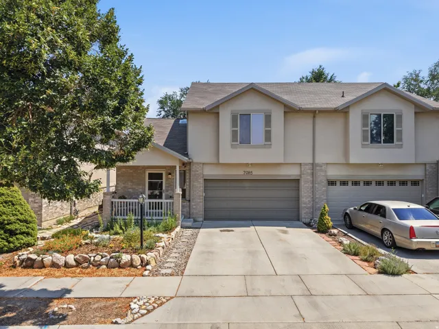 Multi-level residence featuring a covered front porch, integrated garage, and a landscaped front yard with a rock border