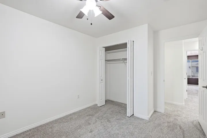Wall-to-wall carpeting, bi-fold closet doors, and ceiling fan
