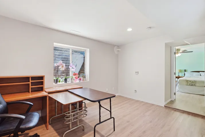 Recessed lighting, light wood-finish flooring, white walls, and a window provide natural illumination