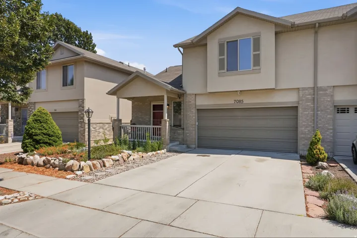 Stucco and brick facade with an attached garage, covered front porch, and concrete driveway
