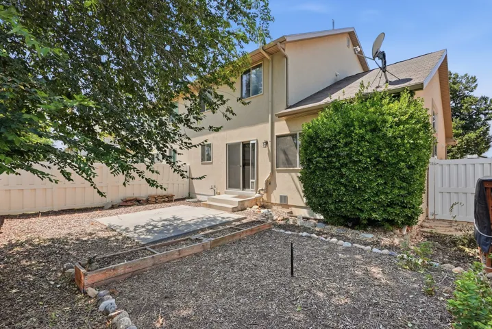 Private backyard with a concrete patio, wood-framed planting beds, and mature landscaping