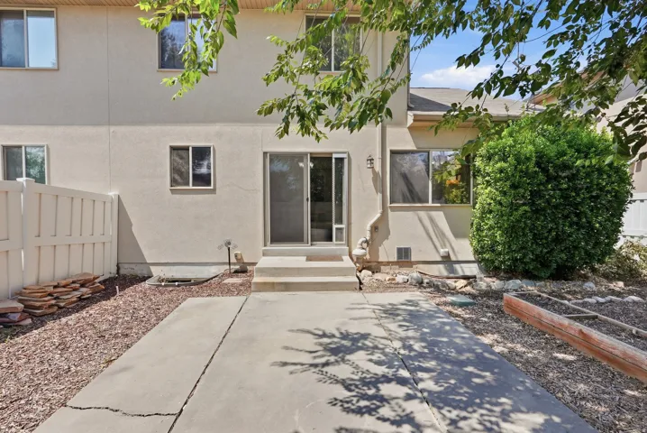 Exterior featuring stucco siding, multiple windows, a sliding glass door, and a concrete patio