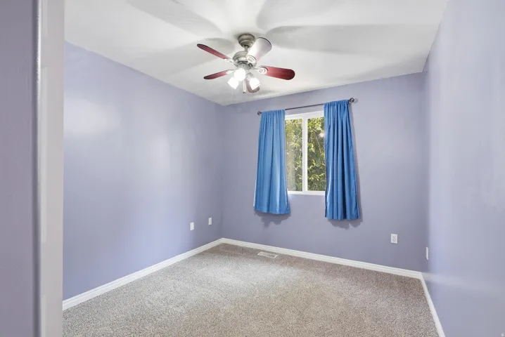 Carpeted room featuring a ceiling fan with integrated lighting