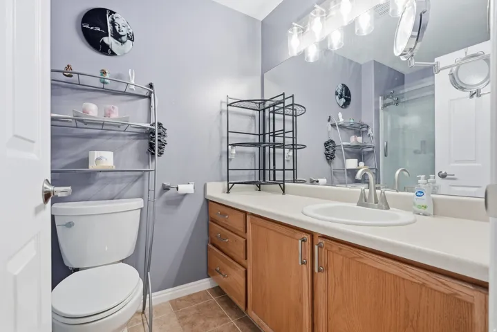 Single vanity with an integrated sink, wood-finish cabinetry, and a full-width mirror