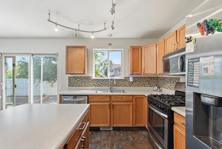 Full kitchen featuring a stainless steel gas range, built-in microwave, and track lighting