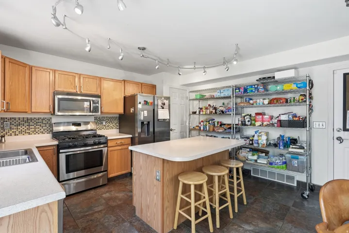 Kitchen featuring wood-finish cabinetry, a central island, stainless steel appliances, and track lighting
