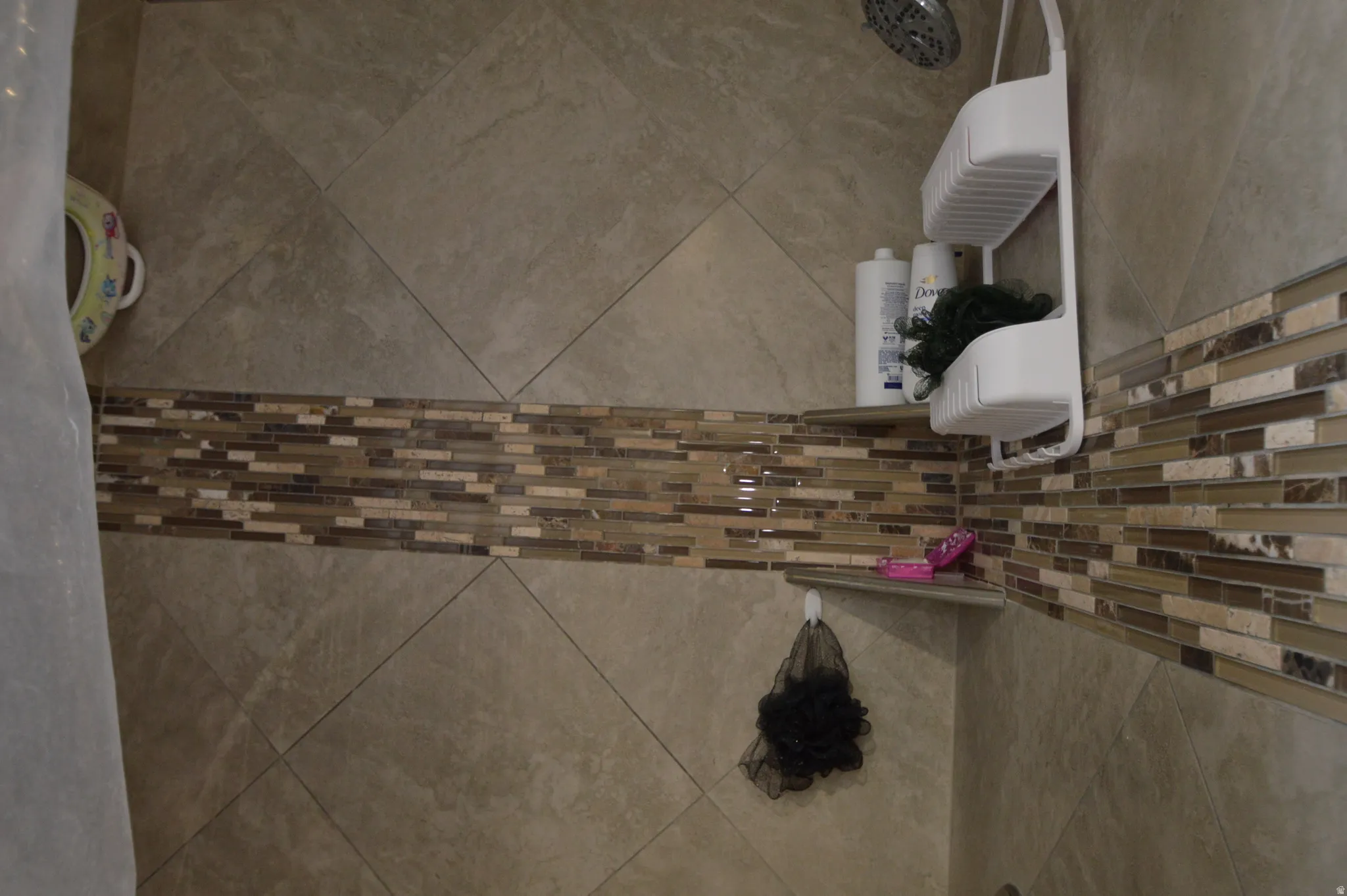 Tiled shower surround with a mosaic accent band, integrated corner shelving, and a rain showerhead
