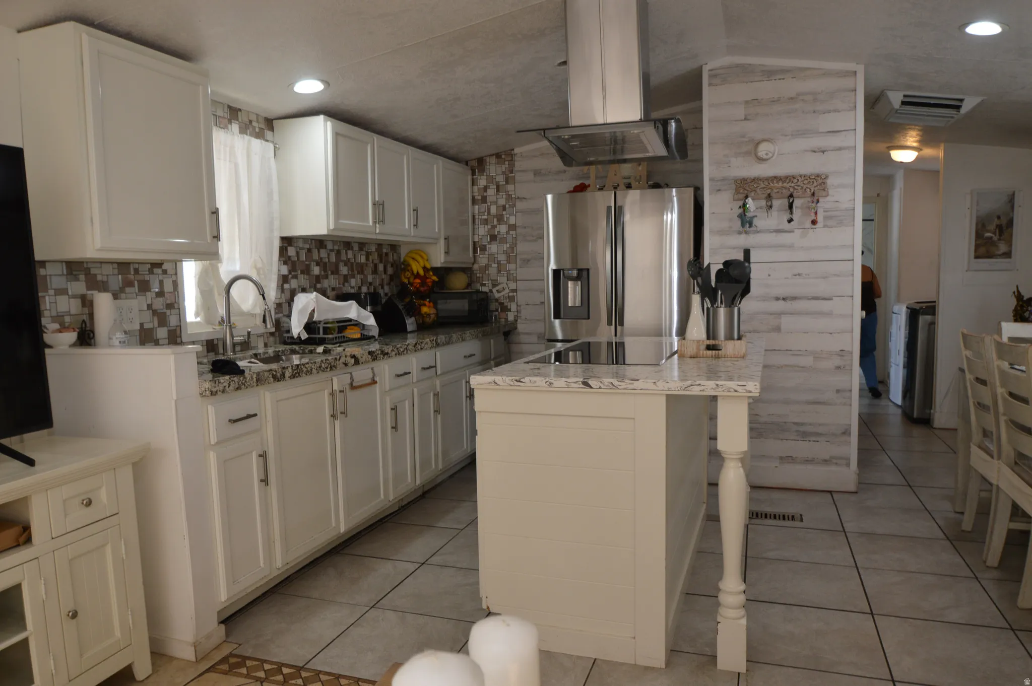 Kitchen featuring white cabinetry, a large center island, stainless steel appliances, and tile flooring