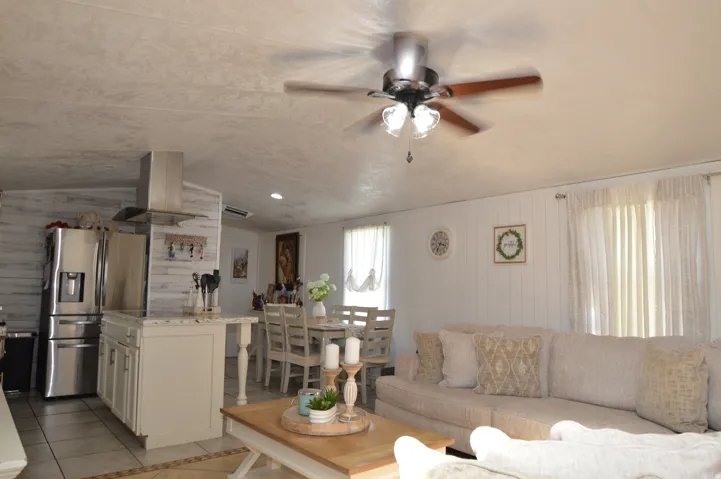 Open concept living space featuring a ceiling fan, kitchen island with built-in cabinetry, stainless steel refrigerator, and a dining area