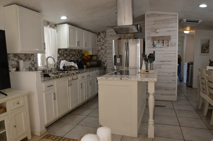 Kitchen featuring white cabinetry, a large center island, stainless steel appliances, and tile flooring