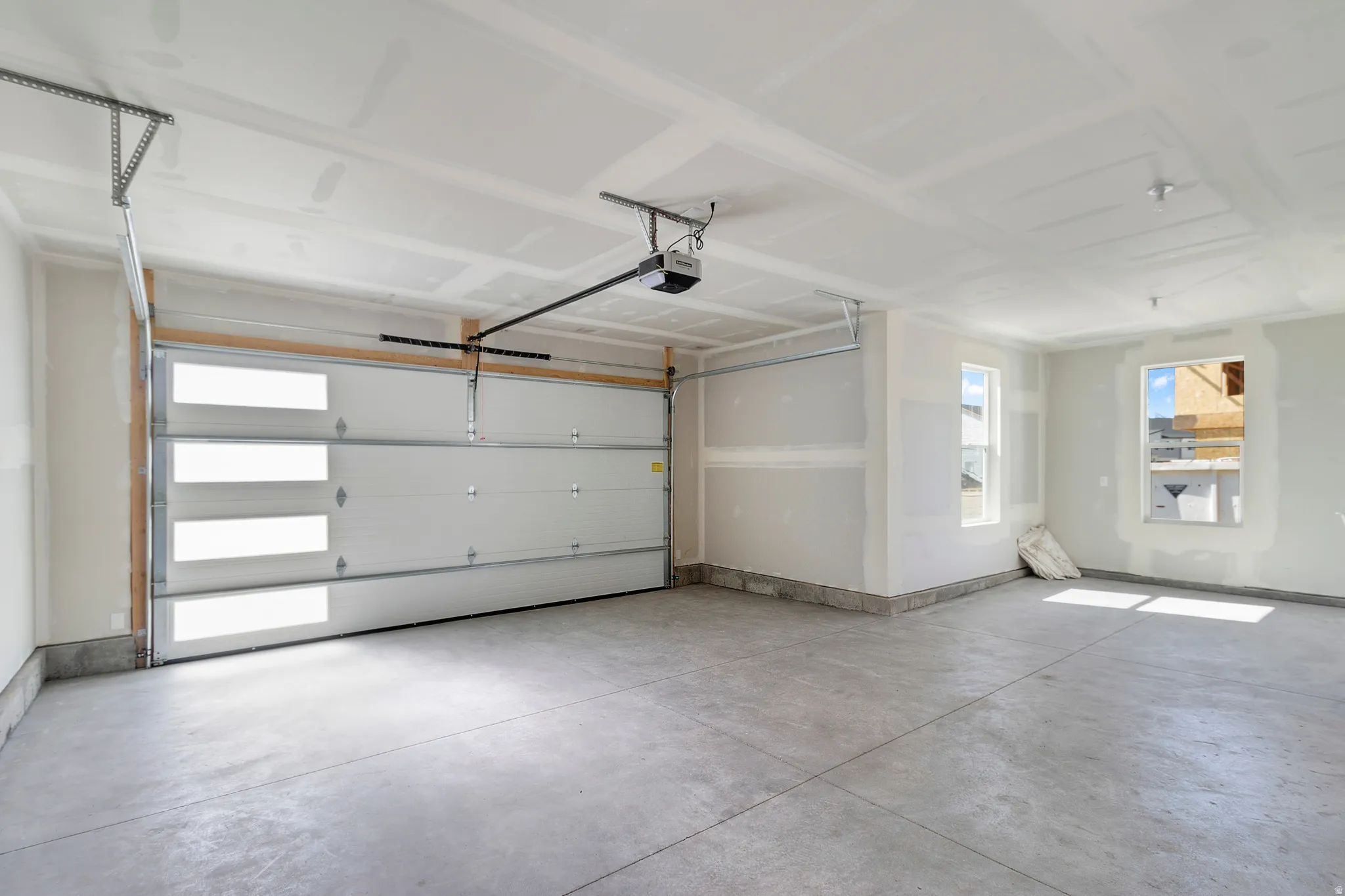 Spacious garage with concrete flooring, two windows, and an automatic overhead door