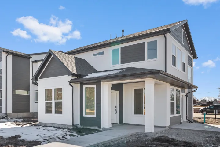 Contemporary exterior featuring a covered entry, white siding, dark gray horizontal siding, and multiple windows