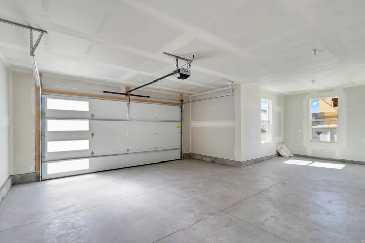 Spacious garage with concrete flooring, two windows, and an automatic overhead door