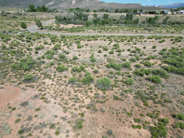 Expansive lot with natural vegetation, a paved road, and distant mountain backdrop