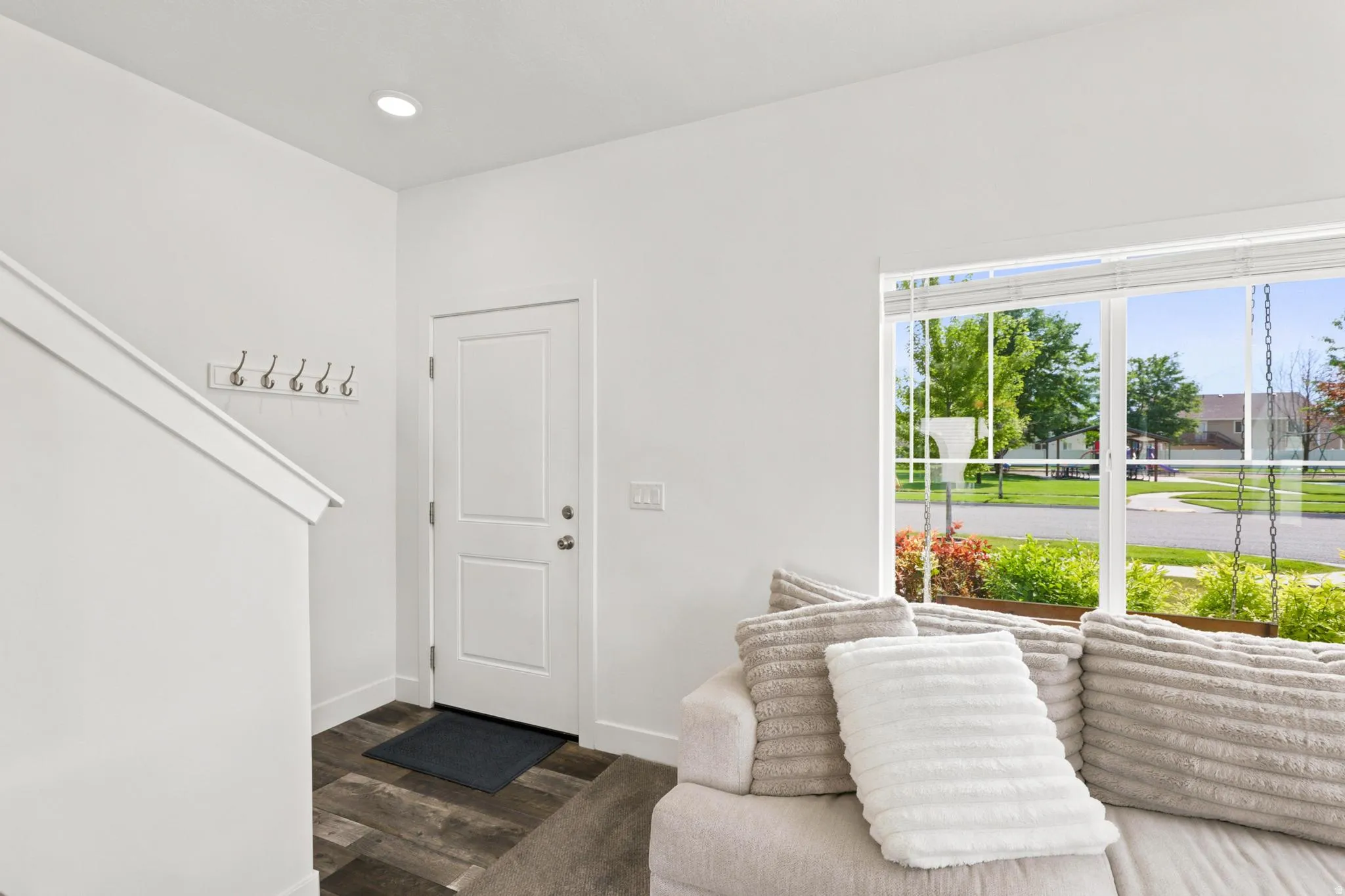 Recessed ceiling lighting, wood-finish flooring, white painted walls, and a large window with white blinds