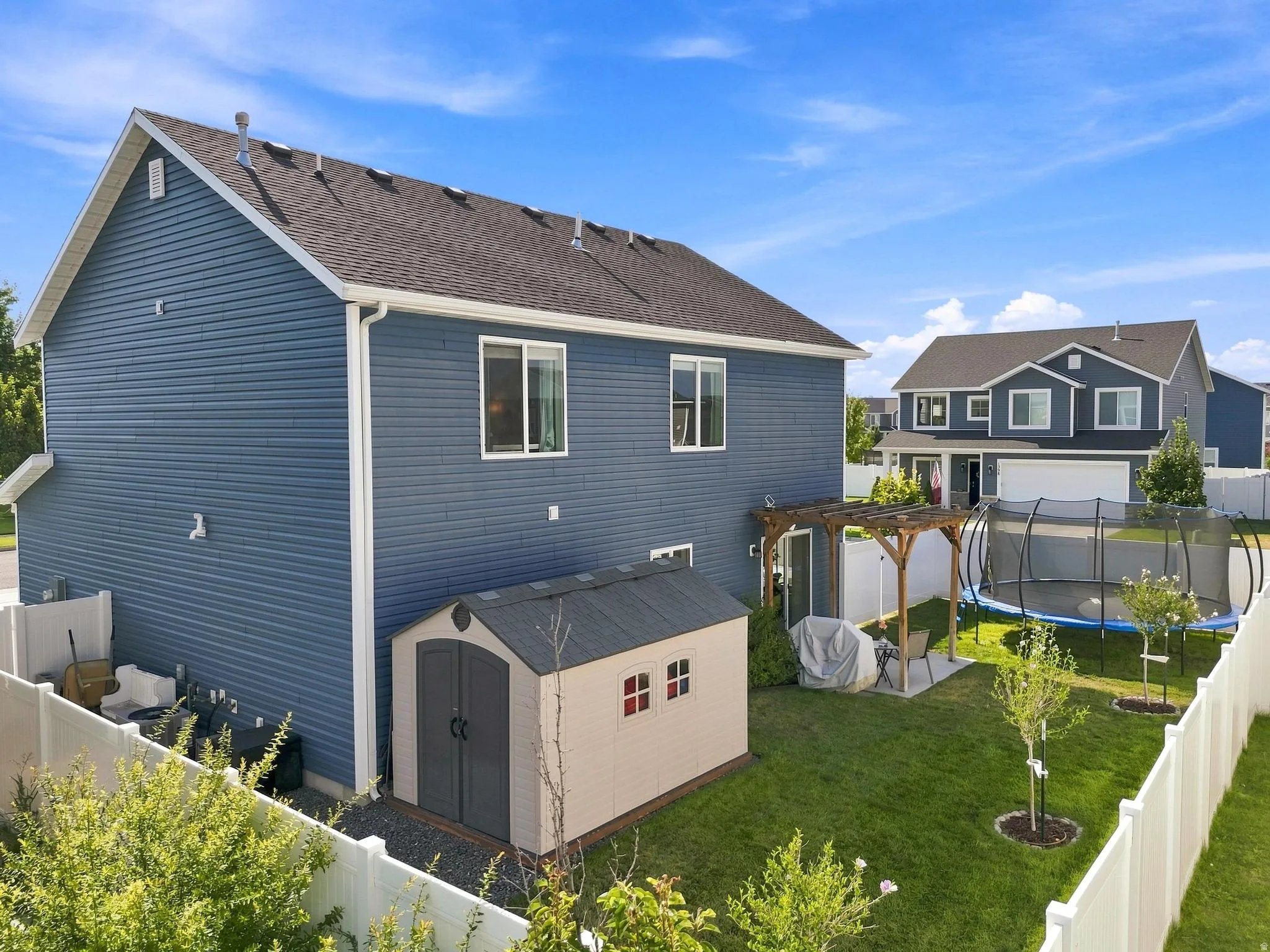 Manicured backyard featuring a privacy fence, wood pergola, and a storage shed