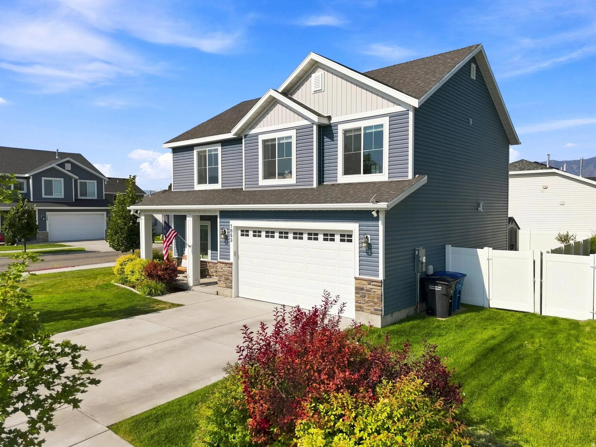 Two-story residence featuring blue siding, white trim, and a prominent front-facing garage