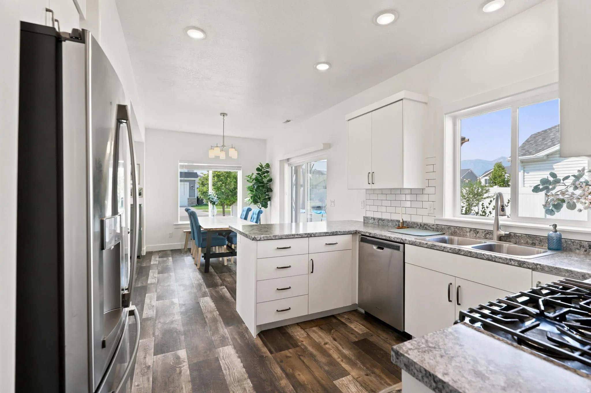 Kitchen featuring white cabinetry, stainless steel appliances, granite countertops, and wood-finish flooring