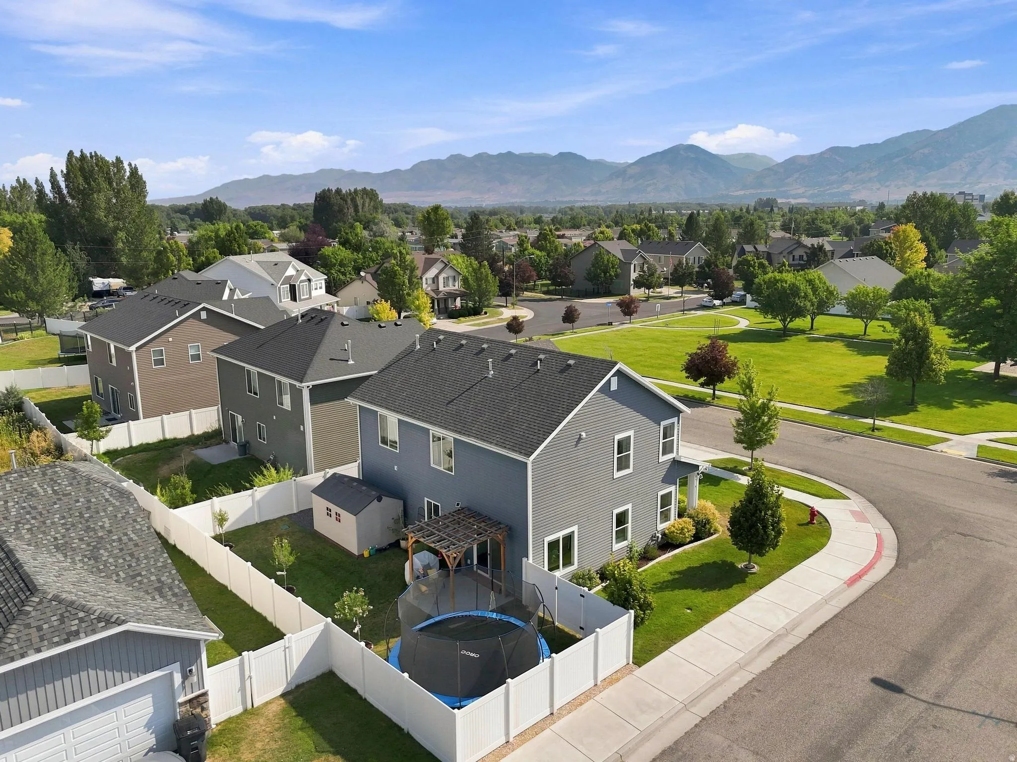 Contemporary two-story residence with a gray exterior, a fenced backyard, and a paved driveway