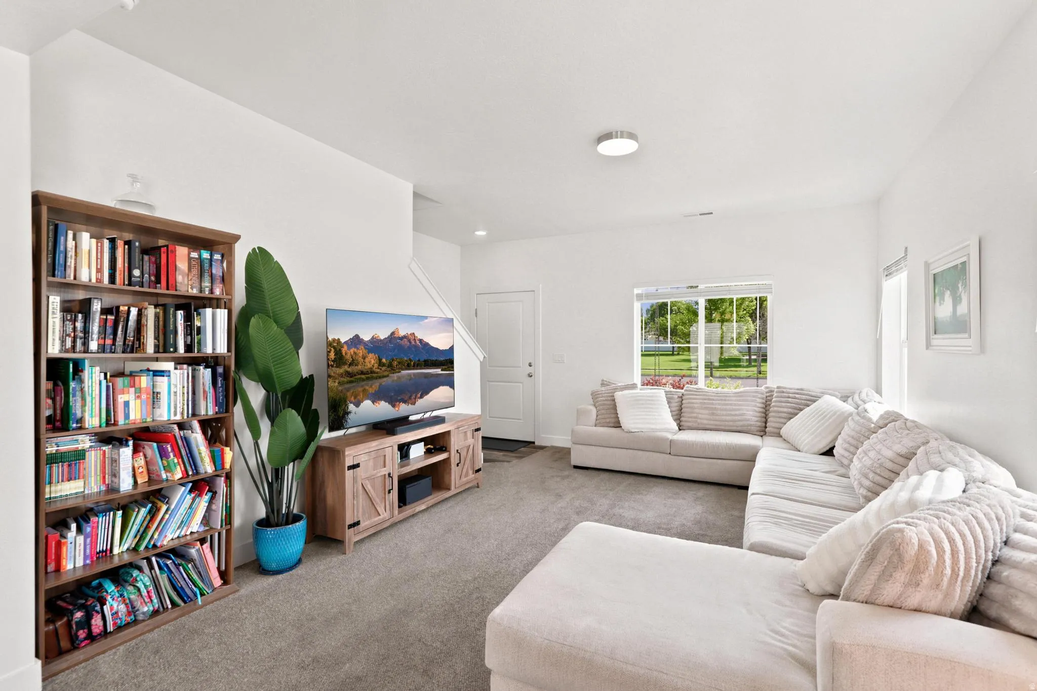 Carpeted living area with white walls, a large window, and recessed lighting