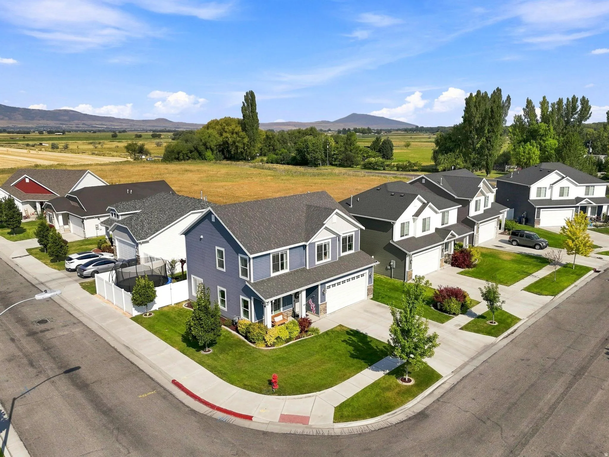 Two-story residence featuring a covered front porch, attached two-car garage, and a manicured lawn