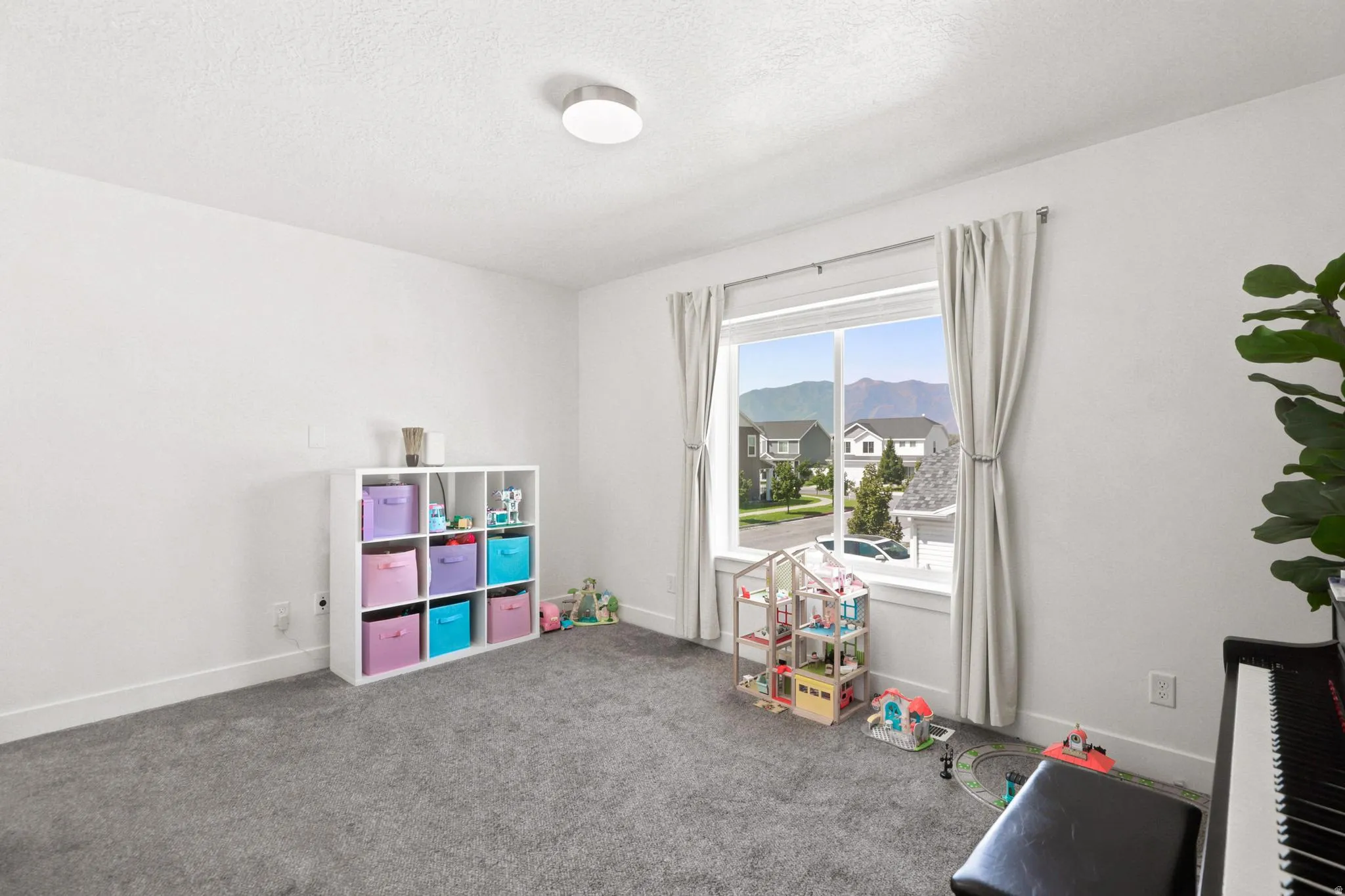 Wall-to-wall carpeting with a white painted wall finish, featuring a large window with white trim, and a flush mount ceiling light fixture