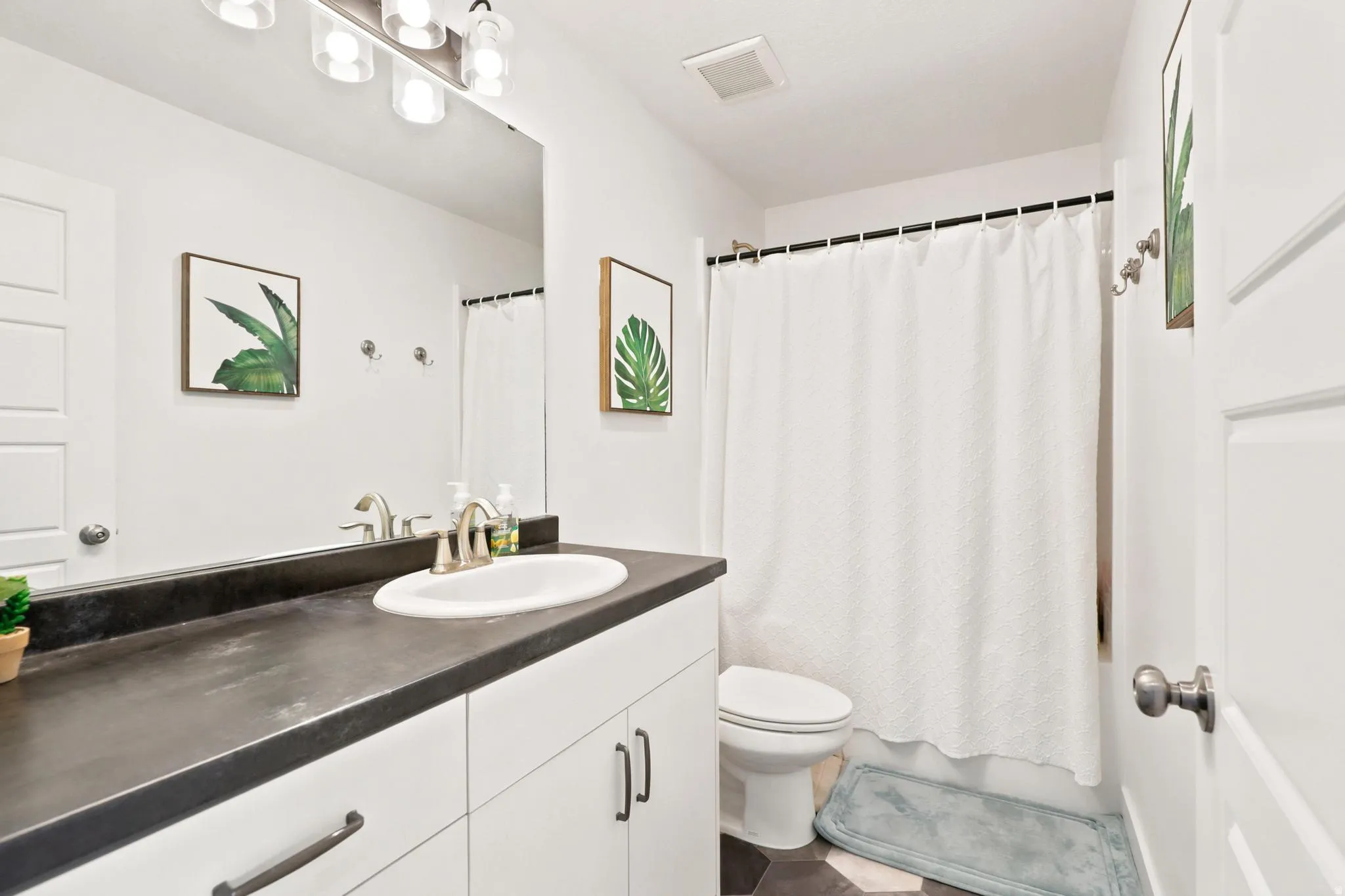 White vanity with dark countertop, undermount sink, and brushed nickel fixtures