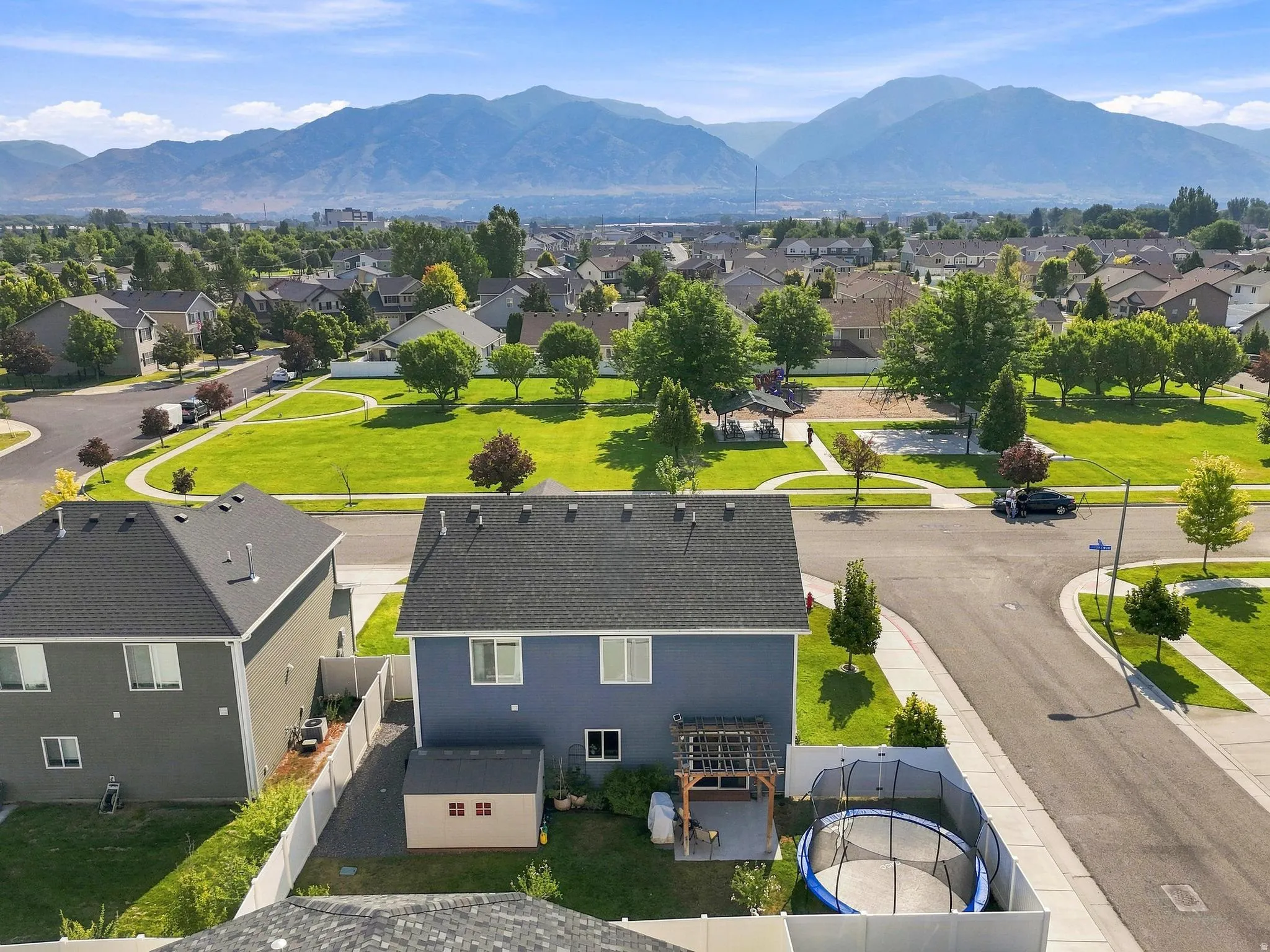 Backyard featuring a paved patio area, an adjacent storage shed, and a surrounding white privacy fence