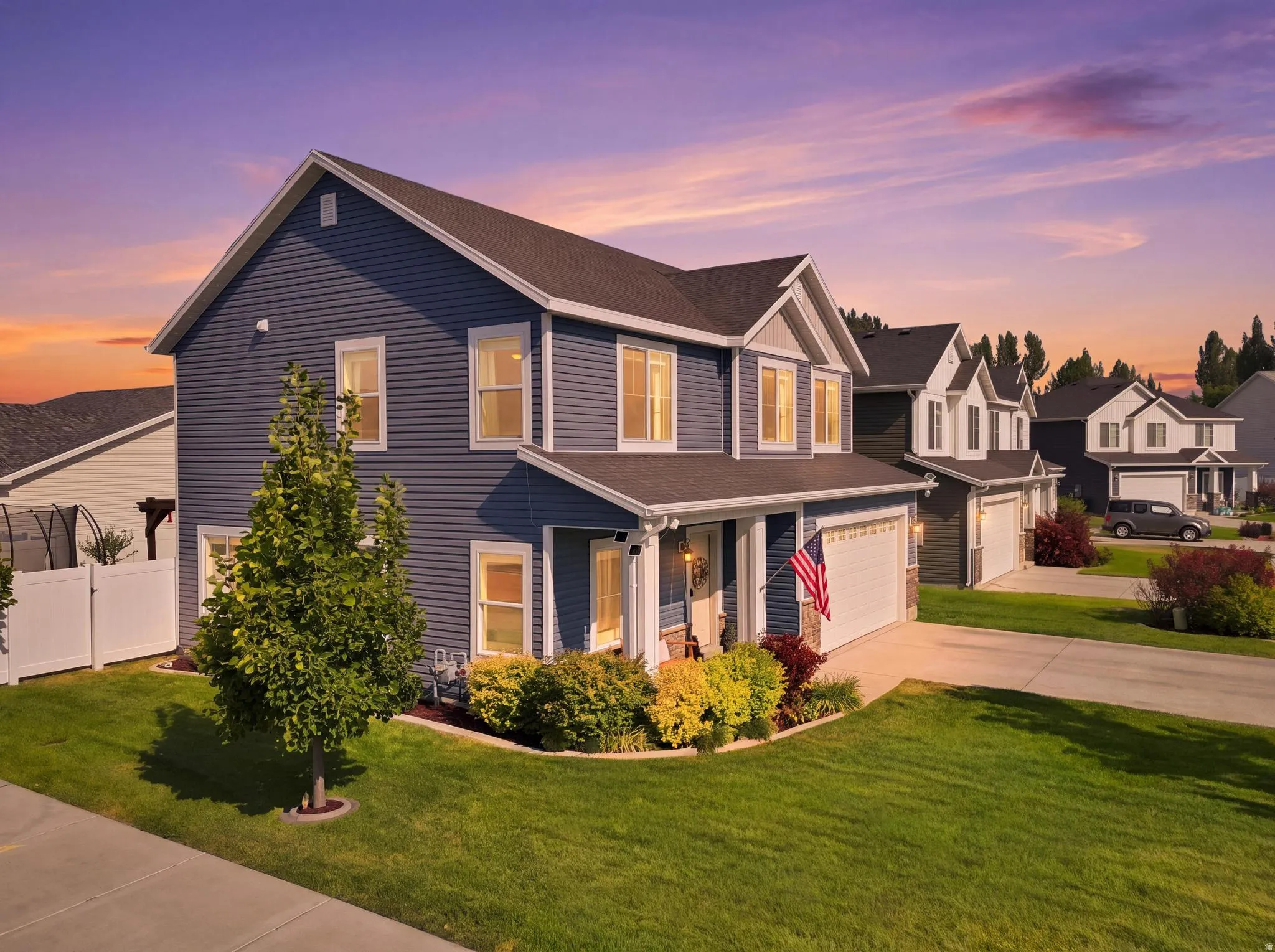 Two-story residence featuring blue siding with white trim accents, an attached two-car garage, and a covered front porch