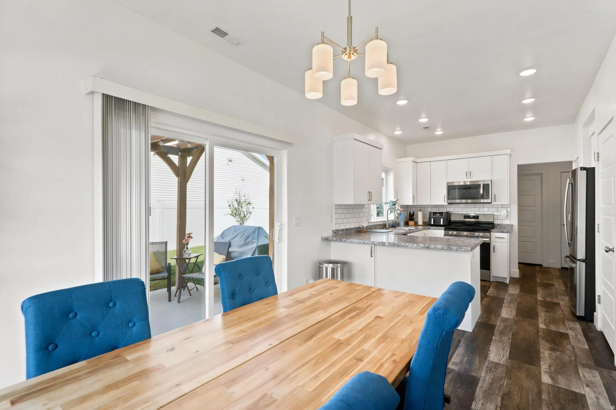 Open-concept kitchen with white cabinetry, stainless steel appliances, and wood-finish flooring