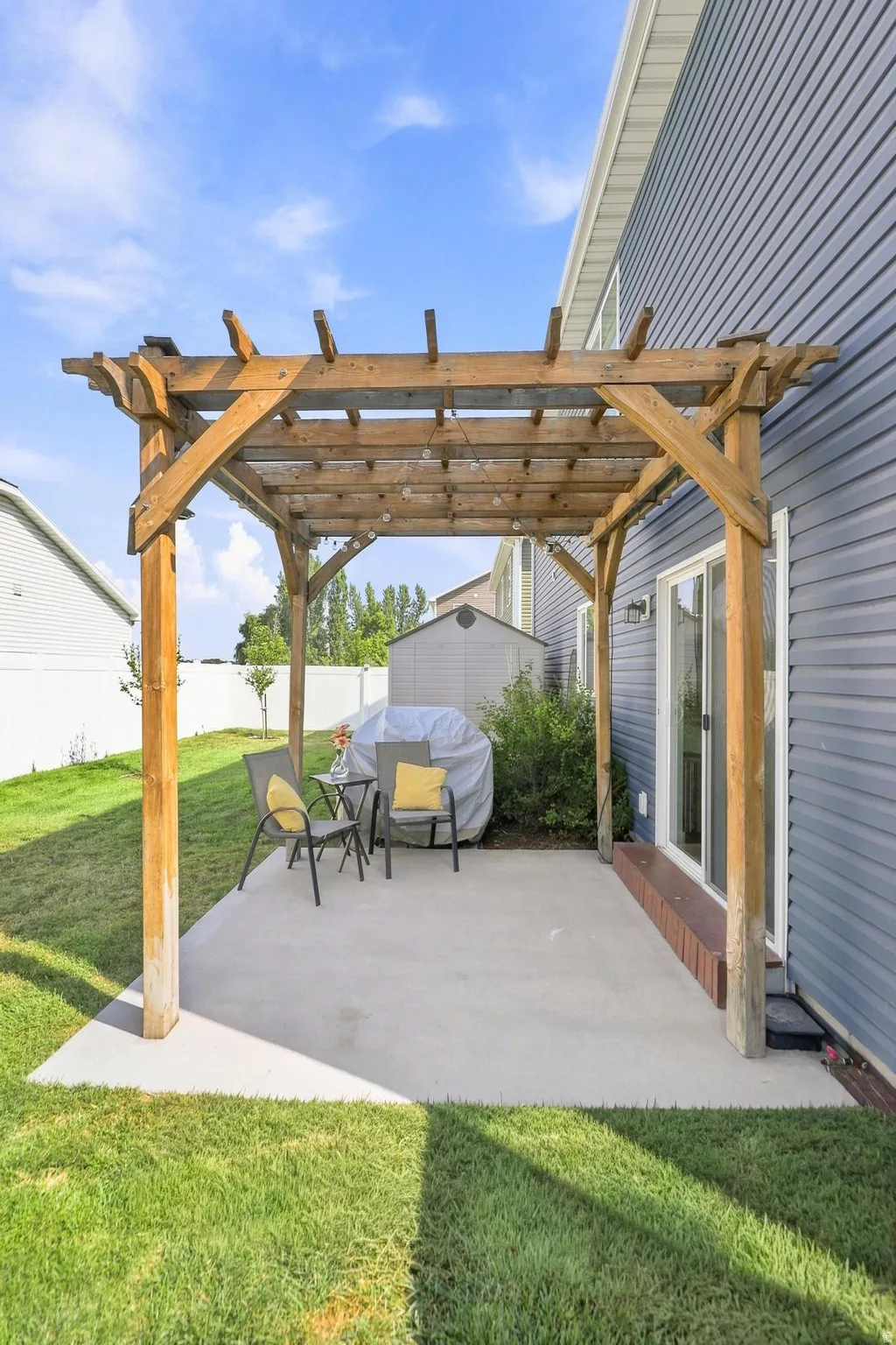 Concrete patio featuring a wooden pergola, sliding glass door, and blue horizontal siding