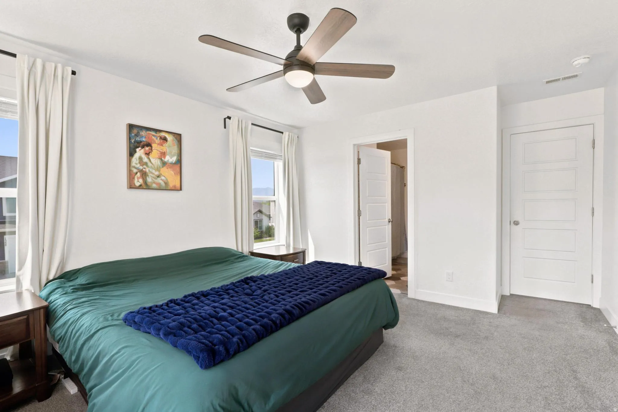 Bright interior with carpet flooring, modern ceiling fan, and white paneled doors