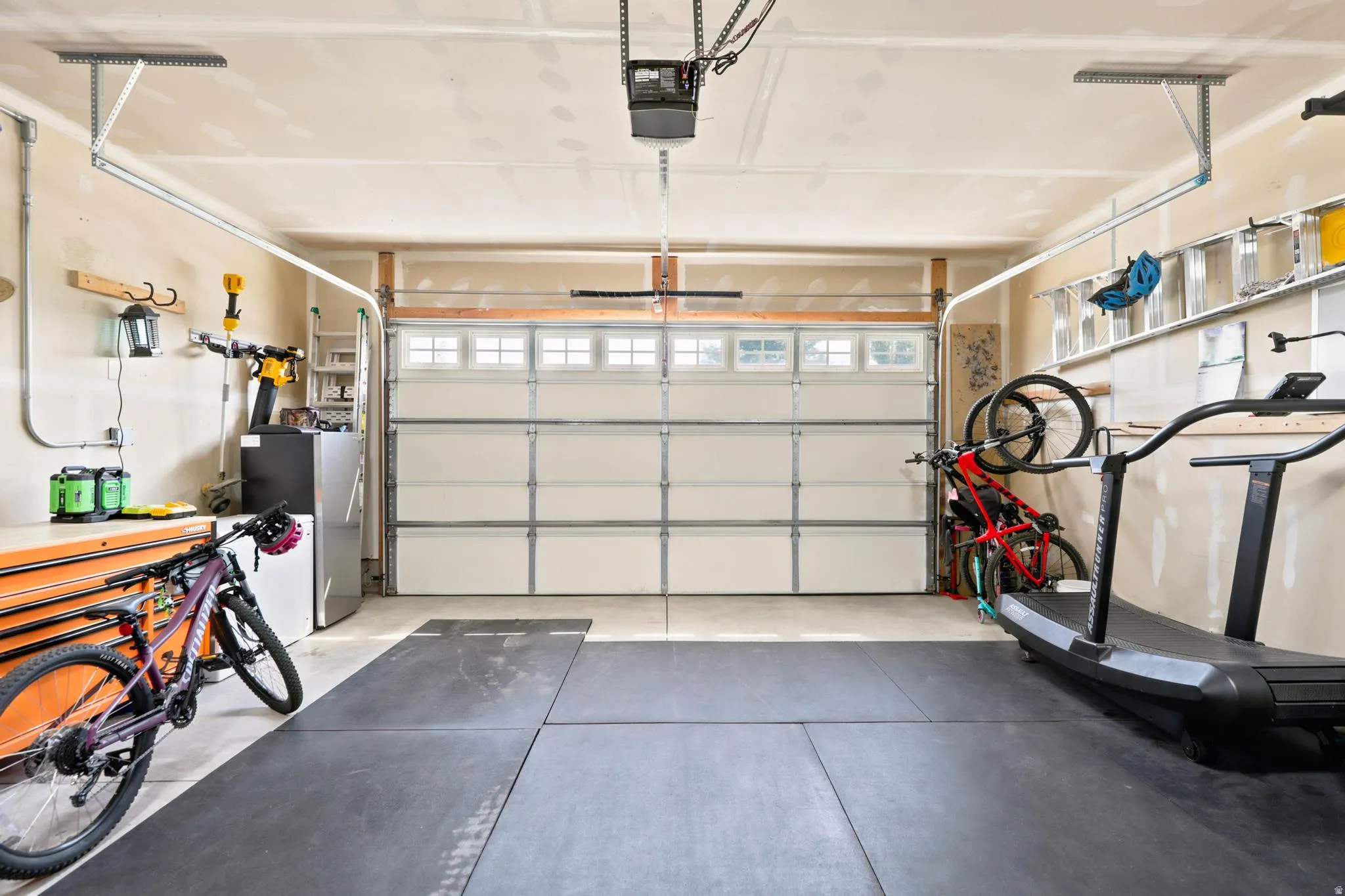 Attached garage featuring a panel garage door with windows, track lighting, and a durable floor surface