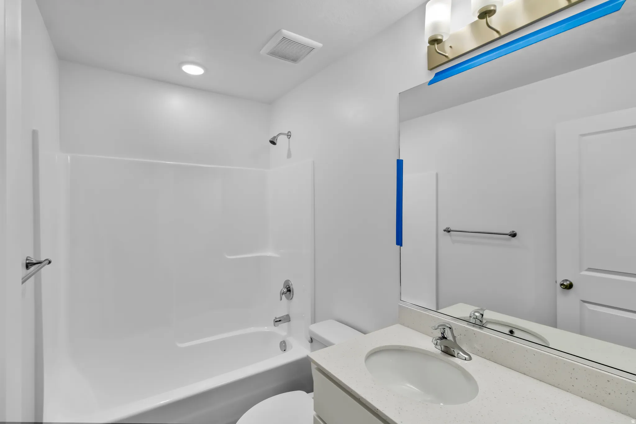 White bathroom featuring a built-in tub with shower, contemporary vanity with an integrated sink, and overhead illumination