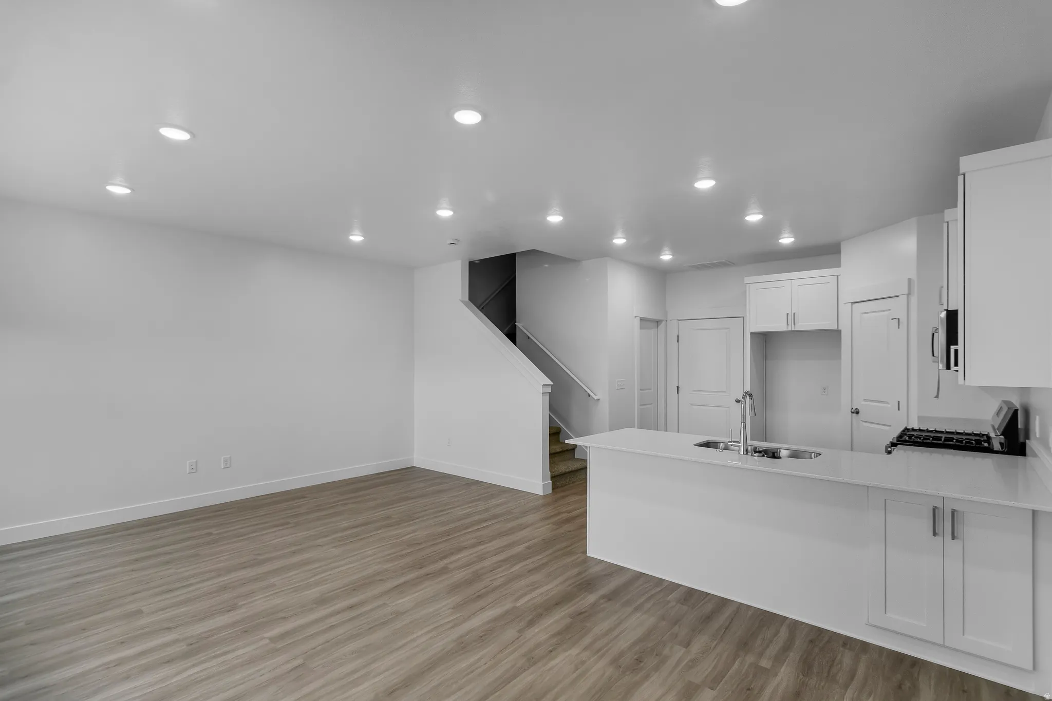 Open-concept living space featuring wood-finish flooring, recessed lighting, and a kitchen island with an integrated sink
