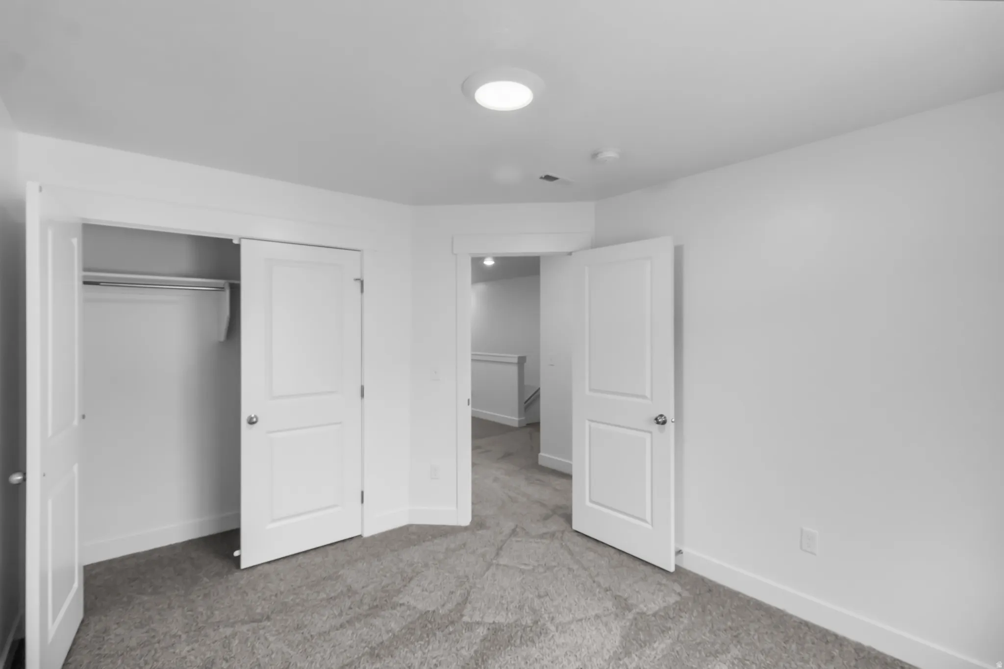 Neutral gray carpeting, white trim, and a white interior door